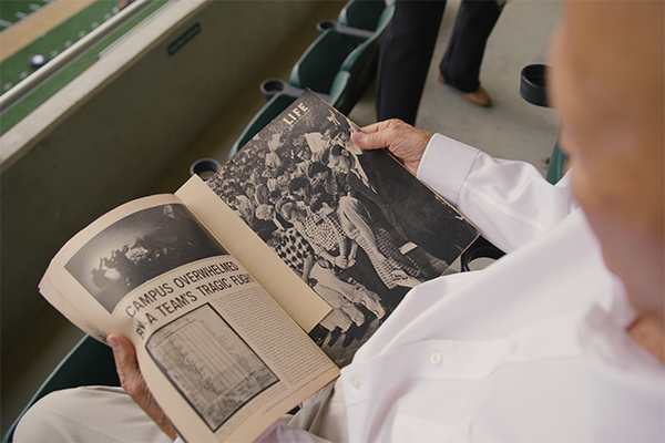 Fred Brown looking at an article about the 1960 Cal Poly football team plane crash.