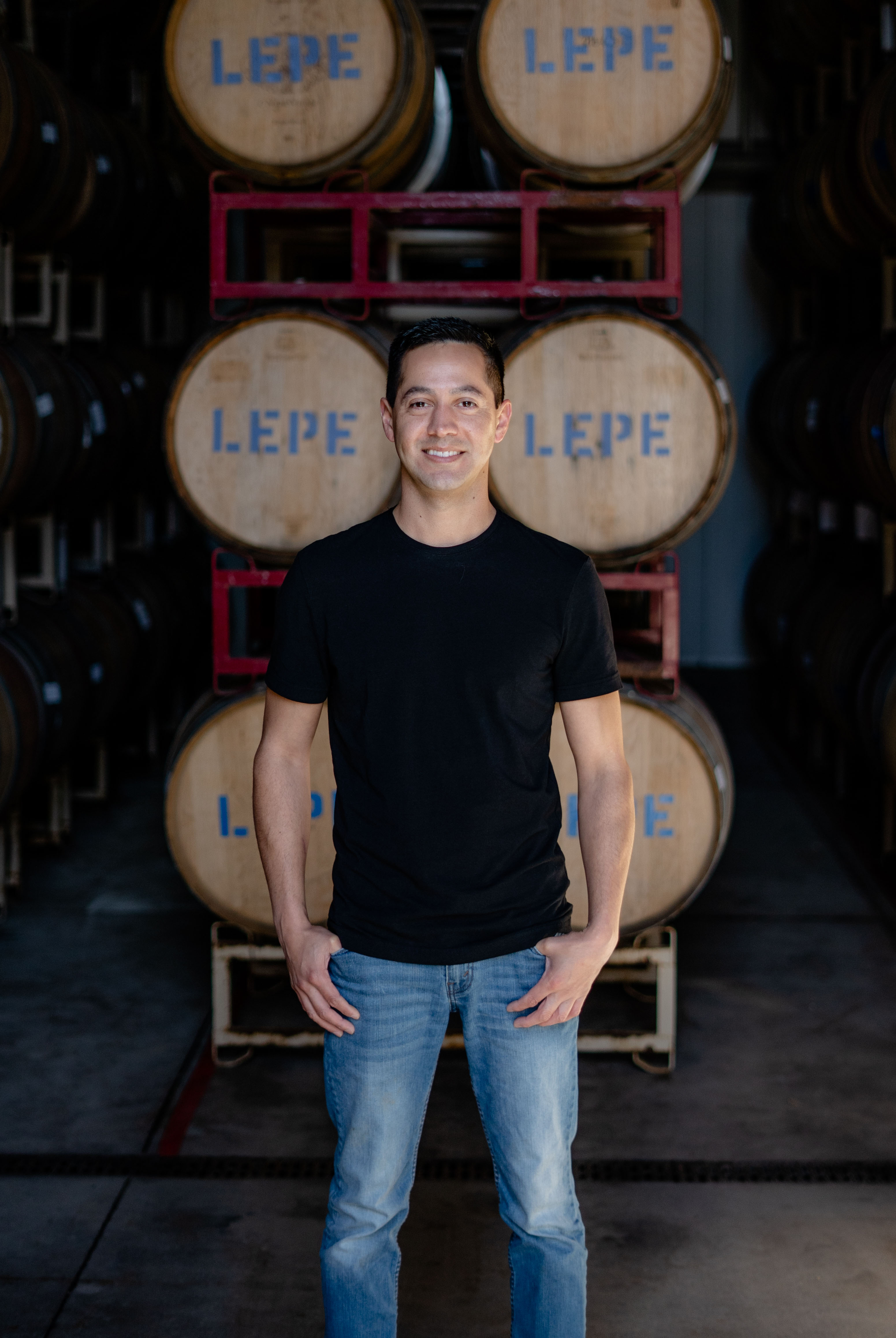 Miguel from Lepe Cellars standing in front of wine barrels