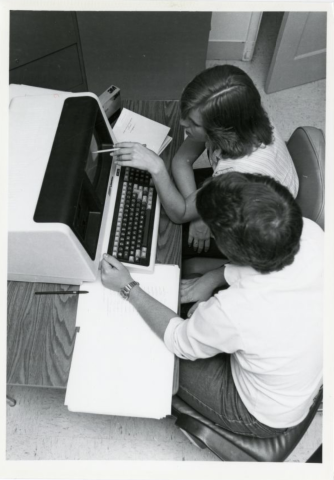 Students sit and work at a computer