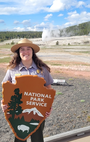 Alumna Rachel Baer holding National Park Service sign.
