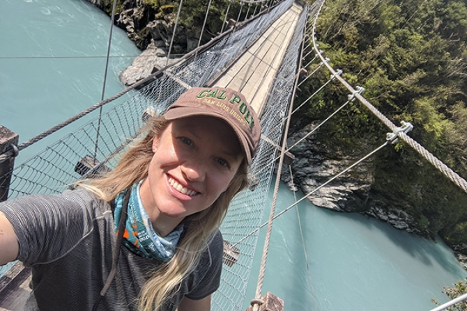 Alumni wearing a Cal Poly hat on a bridge