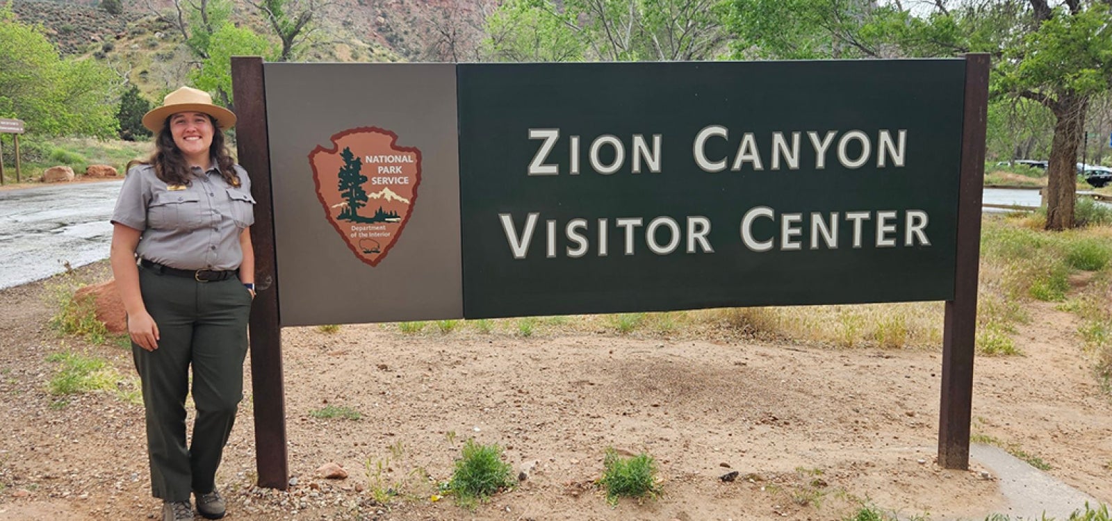 Alumna Rachel Baer in front of Zion Canyon Visitor Center sign.