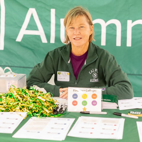 Alumni sitting at a tabling event booth.