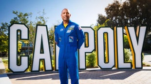 Image of Alumnus Victor Glover in front of the Cal Poly sign on campus