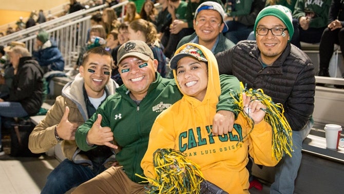 Alumni dressed in Cal Poly gear smiling. 