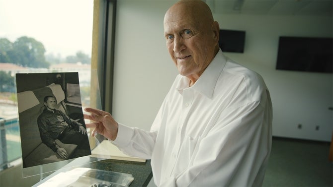 Alumnus Fred Brown holding a photo of himself during his time at Cal Poly.