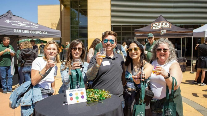 A group smiles at the camera while holding glasses