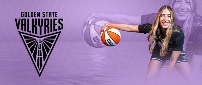 A basketball player holds a ball while smiling at the camera. The Golden State Valkyries logo is next to them
