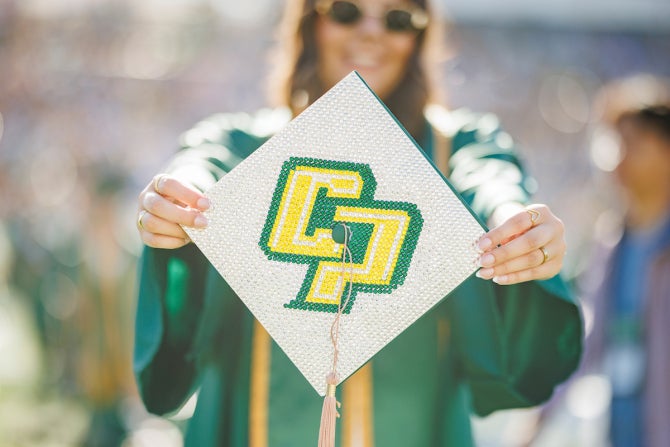 A person displays their decorated graduation cap to the camera