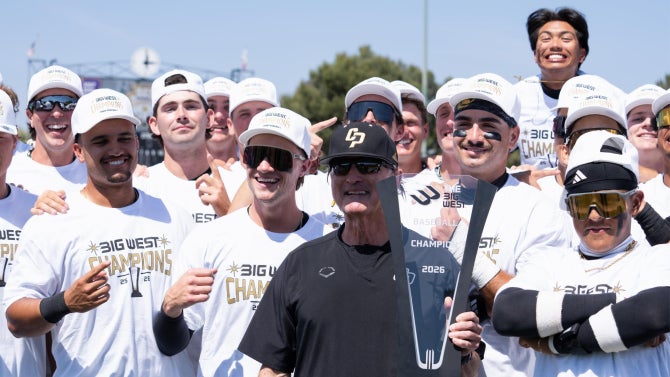Baseball team and coach holding up trophy.
