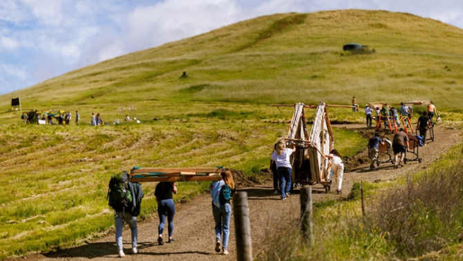 People moving objects up the road towards a hill