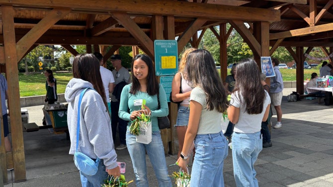 Students chatting as they hold Cal Poly Proud goodie bags.