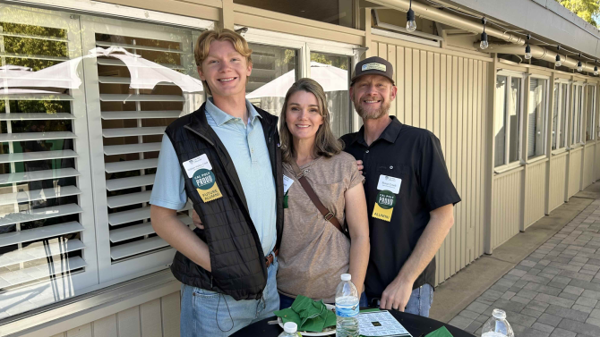 Three people smile for the camera