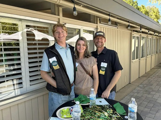 Three people smile for the camera