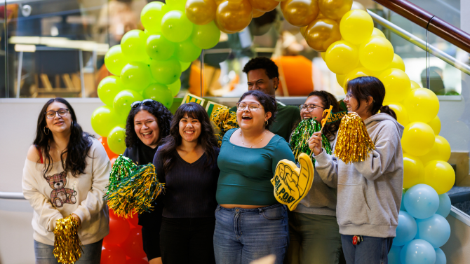 Students smiling in front of a balloon arch