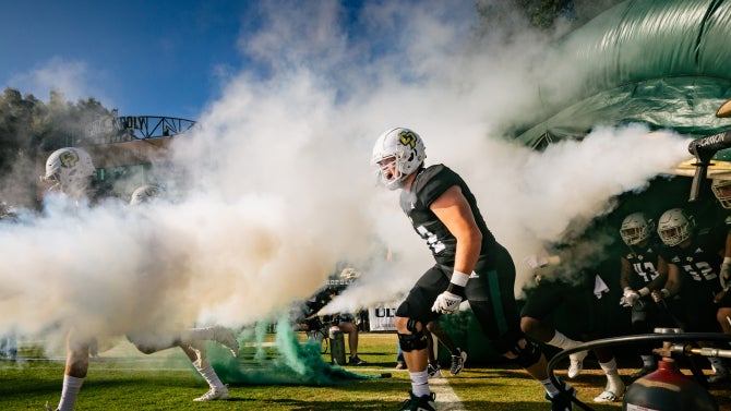 An image of Cal Poly Football athletes running out to the field. 