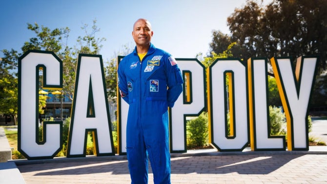 Image of Alumnus Victor Glover in front of the Cal Poly sign on campus